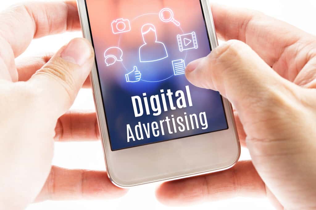 Close up hand holding mobile with Digital Advertising and icons